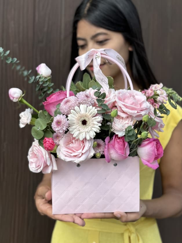 A stylish pink handbag box arrangement with roses, gerberas, and carnations