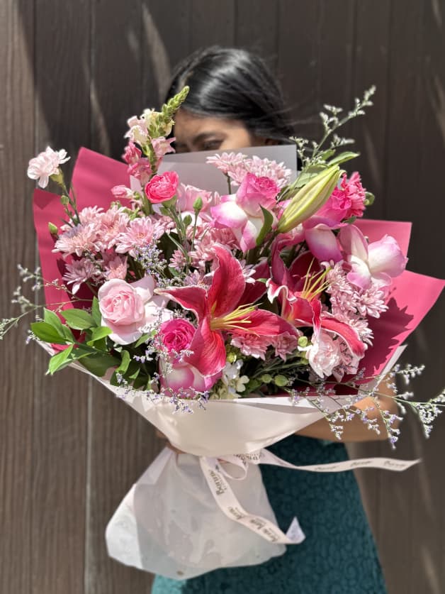 A bold bouquet featuring pink lilies, roses, and carnations in a vibrant wrapper