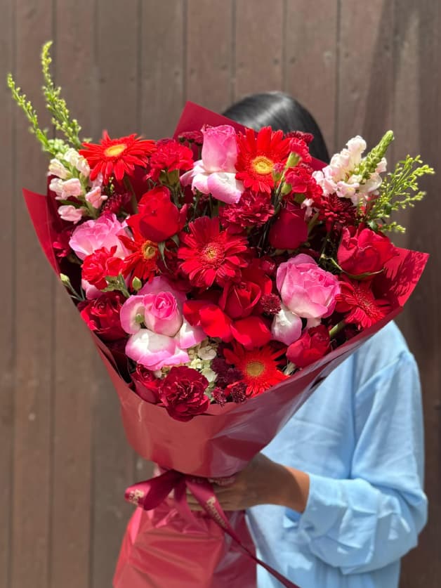 A grand bouquet of red roses, gerberas, and carnations with snapdragons
